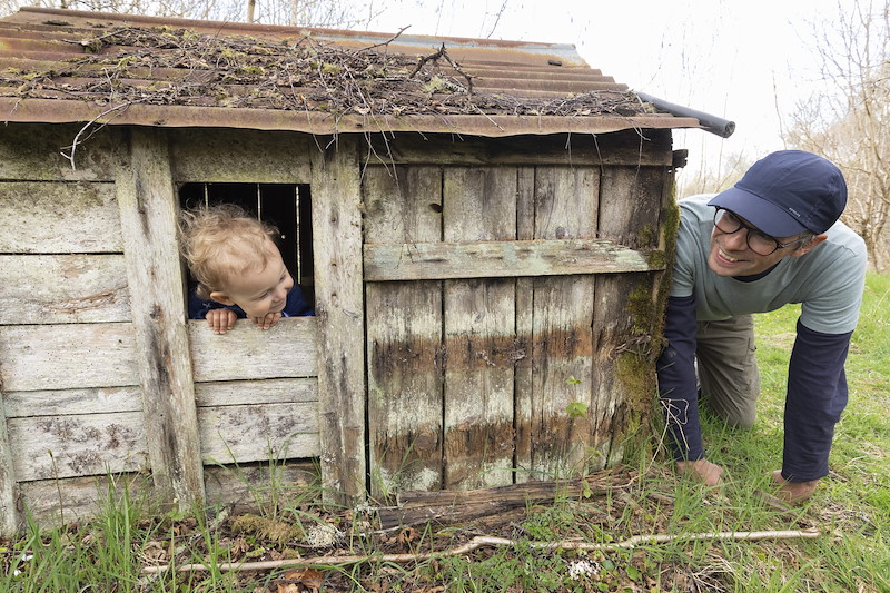 Duncan pepper and young son, Hamish, playing hide and seek around old wooden play shelter in the woods at Cultulich Farm, Aberfeldy, Perthshire