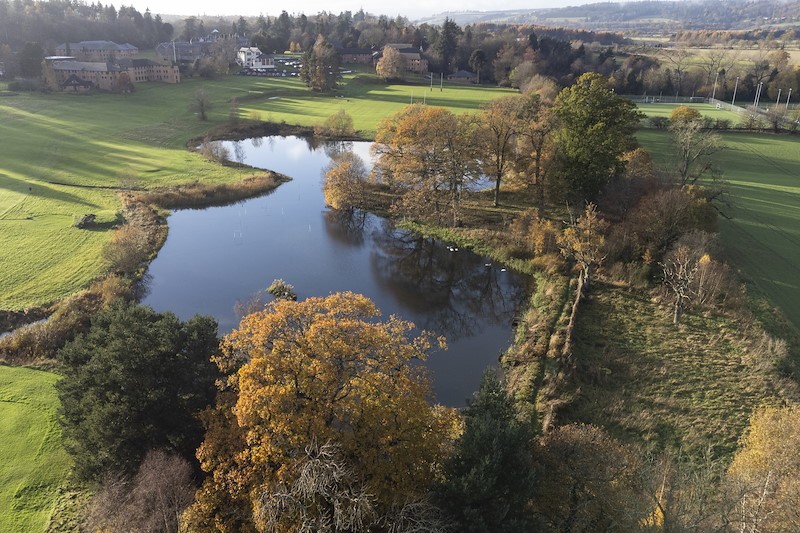 Aerial view of large pond and trees in autumn, Strathallan School, Perthshire