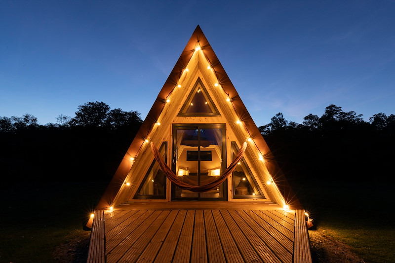 An A-frame glamping pod illuminated at dusk, Torlundy Farm, Lochaber, Scotland, May 2025